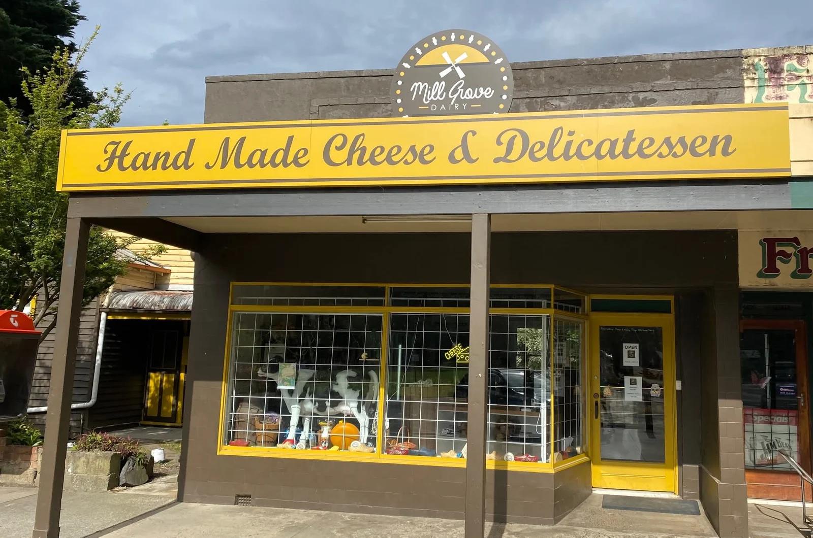 Mill Grove Dairy storefront with yellow Hand Made Cheese & Delicatessen signage